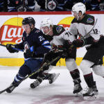 
              Winnipeg Jets center Karson Kuhlman (20) is checked by Arizona Coyotes center Travis Boyd (72) and Coyotes left wing Nick Ritchie (12) during the first period of an NHL hockey game in Winnipeg, Manitoba, on Sunday Jan. 15, 2023. (Fred Greenslade/The Canadian Press via AP)
            