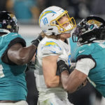 Los Angeles Chargers quarterback Justin Herbert (10) is hit by Jacksonville Jaguars linebacker Travon Walker (44) during the second of an NFL wild-card football game, Saturday, Jan. 14, 2023, in Jacksonville, Fla. (AP Photo/Chris Carlson)