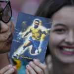 
              A woman kisses a post card of Pele as she waits in line to enter Vila Belmiro stadium where the late Brazilian soccer great lies in state in Santos, Brazil, Monday, Jan. 2, 2023. (AP Photo/Matias Delacroix)
            