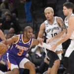 
              Phoenix Suns' Chris Paul (3) drives against San Antonio Spurs' Jeremy Sochan, second from right, and Doug McDermott, right, during the first half of an NBA basketball game, Saturday, Jan. 28, 2023, in San Antonio. (AP Photo/Darren Abate)
            