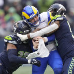 
              Los Angeles Rams quarterback Baker Mayfield, center, is tackled by Seattle Seahawks linebackers Bruce Irvin, right, and Uchenna Nwosu during the second half of an NFL football game Sunday, Jan. 8, 2023, in Seattle. (AP Photo/Stephen Brashear)
            