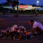 
              FILE - A person pays his respects outside the scene of a shooting at a supermarket, in Buffalo, N.Y., Sunday, May 15, 2022. The Buffalo Bills have been a reliable bright spot for a city that has been shaken by a racist mass shooting and back-to-back snowstorms in recent months. So when Bills safety Damar Hamlin was critically hurt in a game Monday, the city quickly looked for ways to support the team. (AP Photo/Matt Rourke, File)
            