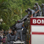
              The remains of late Brazilian soccer great Pele are lowered from a firetruck as his funeral procession arrives to Necropole Ecumenica Memorial Cemetery in Santos, Brazil, Tuesday, Jan. 3, 2023. (AP Photo/Andre Penner)
            