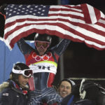 FILE - Ted Ligety of the United States, center, is chaired by teammates as he celebrates after winning the gold medal after the Men's Combined at the Turin 2006 Winter Olympic Games in Sestriere Colle, Italy, Tuesday, Feb. 14, 2006. Mikaela Shiffrin's record 83rd World Cup victory Tuesday, Jan. 24, 2023 is only the latest exploit by an American team that has been producing success after success on the circuit since Daron Rahlves and Bode Miller started it all off more than 20 years ago. (AP Photo/Kevin Frayer, File)