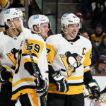 Pittsburgh Penguins left wing Jake Guentzel (59) smiles as he celebrates after his second goal against the Arizona Coyotes with Penguins center Sidney Crosby (87) and defenseman Jan Rutta, left, during the second period of an NHL hockey game in Tempe, Ariz., Sunday, Jan. 8, 2023. (AP Photo/Ross D. Franklin)