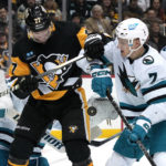 The puck bounces between Pittsburgh Penguins' Jeff Carter (77) and San Jose Sharks' Nico Sturm (7) during the second period of an NHL hockey game in Pittsburgh, Saturday, Jan. 28, 2023. (AP Photo/Gene J. Puskar)