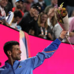 
              Novak Djokovic of Serbia holds up flowers as he leaves Rod Laver Arena after defeating Andrey Rublev of Russia in their quarterfinal match at the Australian Open tennis championship in Melbourne, Australia, Wednesday, Jan. 25, 2023. (AP Photo/Ng Han Guan)
            