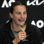 Aryna Sabalenka of Belarus holds up a glass of champagne at a press conference after defeating Elena Rybakina of Kazakhstan in the women's singles final at the Australian Open tennis championship in Melbourne, Australia, Saturday, Jan. 28, 2023. (AP Photo/Dita Alangkara)