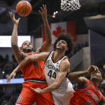 St. John's Joel Soriano (11) reaches for a rebound against UConn's Andre Jackson Jr. (44) as St. John's AJ Storr (2) defends in the first half of an NCAA college basketball game, Sunday, Jan. 15, 2023, in Hartford, Conn. (AP Photo/Jessica Hill)