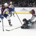 Seattle Kraken left wing Jared McCann (19) falls near the Colorado Avalanche net as Avalanche defensemen Devon Toews (7) and Erik Johnson (6) defend during the second period of an NHL hockey game Saturday, Jan. 21, 2023, in Seattle. (AP Photo/Lindsey Wasson)
