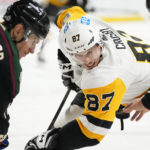 Pittsburgh Penguins center Sidney Crosby (87) watches the puck as linesman Trent Knorr, right, drops the puck on a face off against Arizona Coyotes center Nick Bjugstad, left, during the second period of an NHL hockey game in Tempe, Ariz., Sunday, Jan. 8, 2023. (AP Photo/Ross D. Franklin)