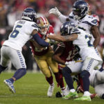 San Francisco 49ers running back Christian McCaffrey, middle, runs against Seattle Seahawks safety Quandre Diggs (6), linebacker Boye Mafe (53) and safety Ryan Neal during the second half of during the second half of an NFL wild card playoff football game in Santa Clara, Calif., Saturday, Jan. 14, 2023. (AP Photo/Godofredo A. Vásquez)