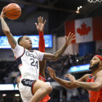 UConn's Jordan Hawkins, left, winds up to dunk the ball against St. John's AJ Storr, back, and St. John's Joel Soriano, right, in the first half of an NCAA college basketball game, Sunday, Jan. 15, 2023, in Hartford, Conn. (AP Photo/Jessica Hill)