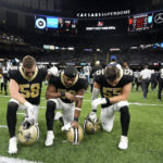 New Orleans Saints linebacker Ty Summers, from left, linebacker Andrew Dowell and linebacker Kaden Elliss say a prayer on the field for Buffalo Bills player Damar Hamlin after an NFL football game between the Carolina Panthers and the New Orleans Saints in New Orleans, Sunday, Jan. 8, 2023. (AP Photo/Gerald Herbert)