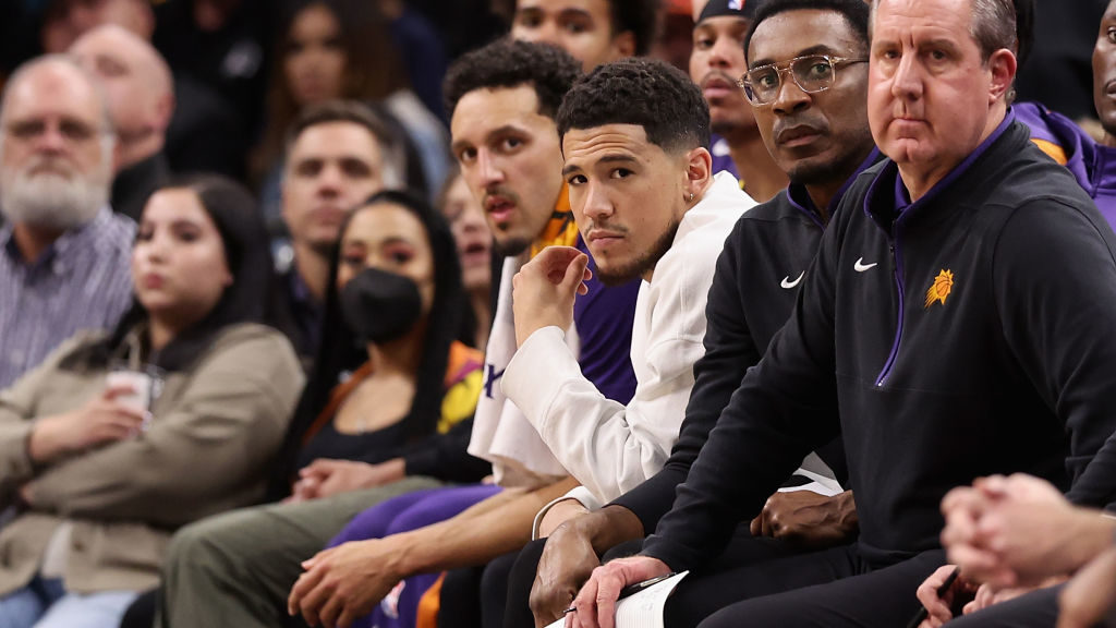 Devin Booker #1 of the Phoenix Suns watches from the bench during the second half of the NBA game a...