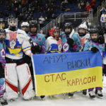 
              Vermont Flames Academy and Ukraine hockey players stand together after a game at the International Peewee Tournament in Quebec City, Friday, Feb. 17, 2023. Ukraine lost 2-1 to Vermont Flames Academy. Written on the top of the flag is the name of Amur Whiskey, who died in the war and was the father of one of the players on the team. The bottom of the flag has the name Stas Karlson, who is the father of another player and is still fighting.(Jacques Boissinot/The Canadian Press via AP)
            