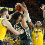 
              Michigan State forward Malik Hall (25) looks to pass as Michigan center Hunter Dickinson (1) and guard Dug McDaniel (0) defend during the first half of an NCAA college basketball game, Saturday, Feb. 18, 2023, in Ann Arbor, Mich. (AP Photo/Carlos Osorio)
            