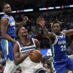 Minnesota Timberwolves guard Anthony Edwards, center, drives to the basket as Dallas Mavericks' Theo Pinson, left, and Reggie Bullock (25) defend in the first half of an NBA basketball game, Monday, Feb. 13, 2023, in Dallas. (AP Photo/Tony Gutierrez)