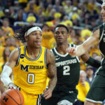 Michigan guard Dug McDaniel (0) drives as Michigan State forward Joey Hauser (10) defends during the second half of an NCAA college basketball game, Saturday, Feb. 18, 2023, in Ann Arbor, Mich. (AP Photo/Carlos Osorio)