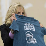 
              FILE - First lady Jill Biden holds up a Philadelphia Eagles shirt while sorting children's clothes at the FEMA State Disaster Recovery Center in Bowling Green, Ky., Jan. 14, 2022. (AP Photo/Michael Clubb, File)
            