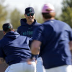 Seattle Mariners manager Scott Servais watches players warmup during spring training baseball practice Saturday, Feb. 18, 2023, in Peoria, Ariz. (AP Photo/Charlie Riedel)