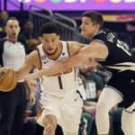 
              Milwaukee Bucks guard Grayson Allen (12) reaches in on Phoenix Suns guard Devin Booker (1) during the first half of an NBA basketball game Sunday, Feb. 26, 2023, in Milwaukee. (AP Photo/Jeffrey Phelps)
            