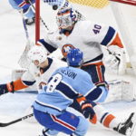 Montreal Canadiens' Mike Matheson (8) scores against New York Islanders goaltender Semyon Varlamov as Islanders' Adam Pelech (3) tries to block the shot during overtime in an NHL hockey game in Montreal, Saturday, Feb. 11, 2023. (Graham Hughes/The Canadian Press via AP)