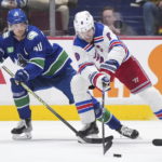 New York Rangers' Jacob Trouba (8) reaches for the puck in front of Vancouver Canucks' Elias Pettersson (40) during the second period of an NHL hockey game Wednesday, Feb. 15, 2023, in Vancouver, British Columbia. (Darryl Dyck/The Canadian Press via AP)