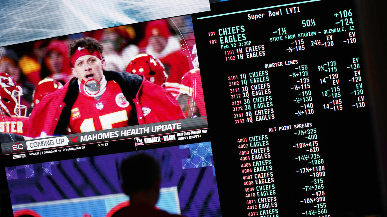 A person gambles as betting odds for NFL football's Super Bowl are displayed on monitors at the Cir...