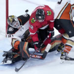 Chicago Blackhawks' Reese Johnson (52) falls between Anaheim Ducks goaltender Anthony Stolarz (41) and Simon Benoit as the puck bounces off the wall behind them during the third period of an NHL hockey game Tuesday, Feb. 7, 2023, in Chicago. The Ducks won in overtime 3-2. (AP Photo/Charles Rex Arbogast)