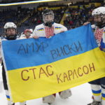
              Ukrainian hockey players Ivan Bilozerov, left, Matvii Kulish, center, and Ihor Malovanyi hold a Ukrainian flag after they lost to Vermont Flames Academy at the International Peewee Tournament in Quebec City, Friday, Feb. 17, 2023. Written on the top of the flag is the name of Amur Whiskey, who died in the war and was the father of one of the players on the team. The bottom of the flag has the name Stas Karlson, who is the father of another player and is still fighting. (Jacques Boissinot/The Canadian Press via AP)
            