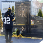 
              FILE - A fan takes a photo of the flowers and Terrible Towels placed at the Immaculate Reception memorial outside Acrisure Stadium on the Northside of Pittsburgh in memory of Pittsburgh Steelers Pro Football Hall of Fame running back Franco Harris, Wednesday, Dec. 21, 2022. While its Super Bowl commercial appearances are few, religion – Christianity especially – is entrenched in football culture. (AP Photo/Gene J. Puskar, File)
            