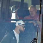 Kansas City Chiefs head coach Andy Reid, top, sits next to the Vince Lombardi Trophy as Travis Kelce, bottom, gets on a bus after returning home a day after winning the NFL Super Bowl 57 football game, Monday, Feb. 13, 2023, in Kansas City, Mo. (AP Photo/Colin E. Braley)