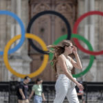 
              FILE - A woman passes by the Olympic rings at the City Hall in Paris, on  July 25, 2022. Latvia is  threatening to boycott next year’s Paris Olympics if athletes from Russia and its ally Belarus are allowed to take part after Russia's invasion of Ukraine. (AP Photo/Lewis Joly, File)
            