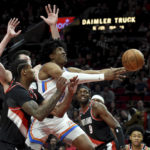 Oklahoma City Thunder forward Jalen Williams, center, drives to the basket on Portland Trail Blazers guard Cam Redish, left, and forward Jerami Grant, right, during the first half of an NBA basketball game in Portland, Ore., Friday, Feb. 10, 2023. (AP Photo/Steve Dykes)