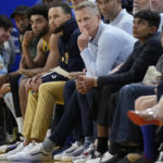 Injured Golden State Warriors guard Stephen Curry, middle left, and head coach Steve Kerr, middle, watch from the bench during the first half of the team's NBA basketball game against the Minnesota Timberwolves in San Francisco, Sunday, Feb. 26, 2023. (AP Photo/Jeff Chiu)