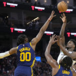 Minnesota Timberwolves guard Anthony Edwards, top right, shoots against Golden State Warriors forward Jonathan Kuminga (00) and forward Kevon Looney during the first half of an NBA basketball game in San Francisco, Sunday, Feb. 26, 2023. (AP Photo/Jeff Chiu)