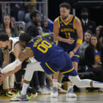 Golden State Warriors forward Jonathan Kuminga (00) reaches for the ball against Minnesota Timberwolves guard Austin Rivers, left, as Klay Thompson (11) watches during the first half of an NBA basketball game in San Francisco, Sunday, Feb. 26, 2023. (AP Photo/Jeff Chiu)