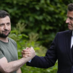 
              FILE - Ukraine President Volodymyr Zelenskyy, left, and France's President Emmanuel Macron shake hands at the end of a press conference at the Mariyinsky Palace in Kyiv, Ukraine, on June 16, 2022. The question of if and how Russia competes at the Olympics hangs over the 2024 Paris Summer Games. One year after the invasion of Ukraine began, Russia's reintegration into the world of sports threatens to create the biggest rift in the Olympic movement since the Cold War. (AP Photo/Natacha Pisarenko, File)
            