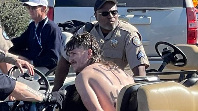 A streaker is detained by police after rushing the 16th hole at the 2023 WM Phoenix Open on Friday,...