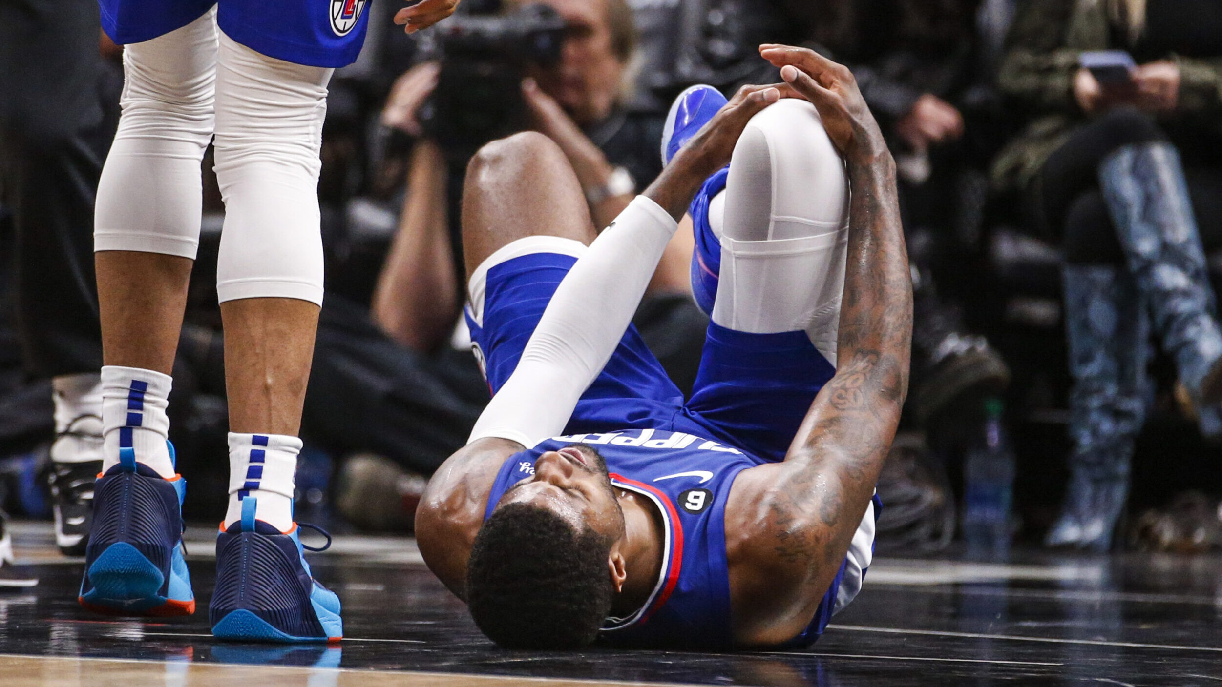 Los Angeles Clippers forward Paul George, right, lies on the court after an injury during the secon...