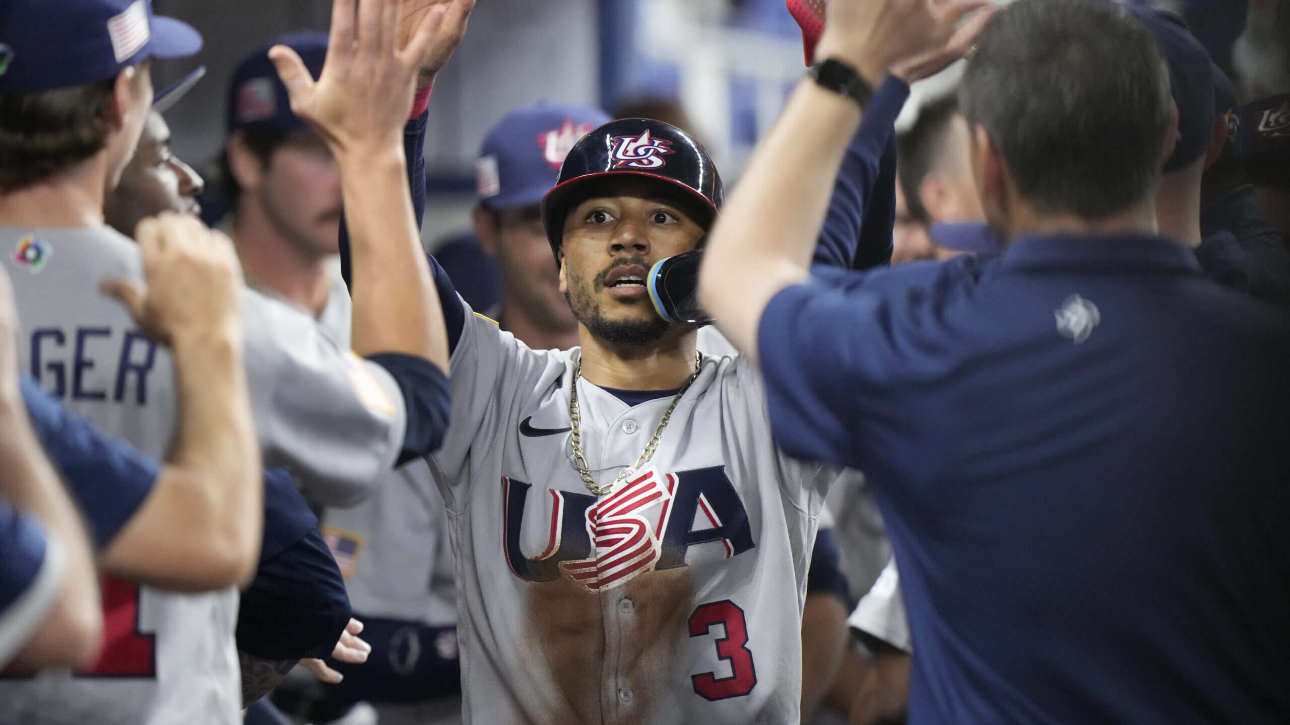 United States' Mookie Betts (3) is congratulated by teammates after he scored on a throwing error b...