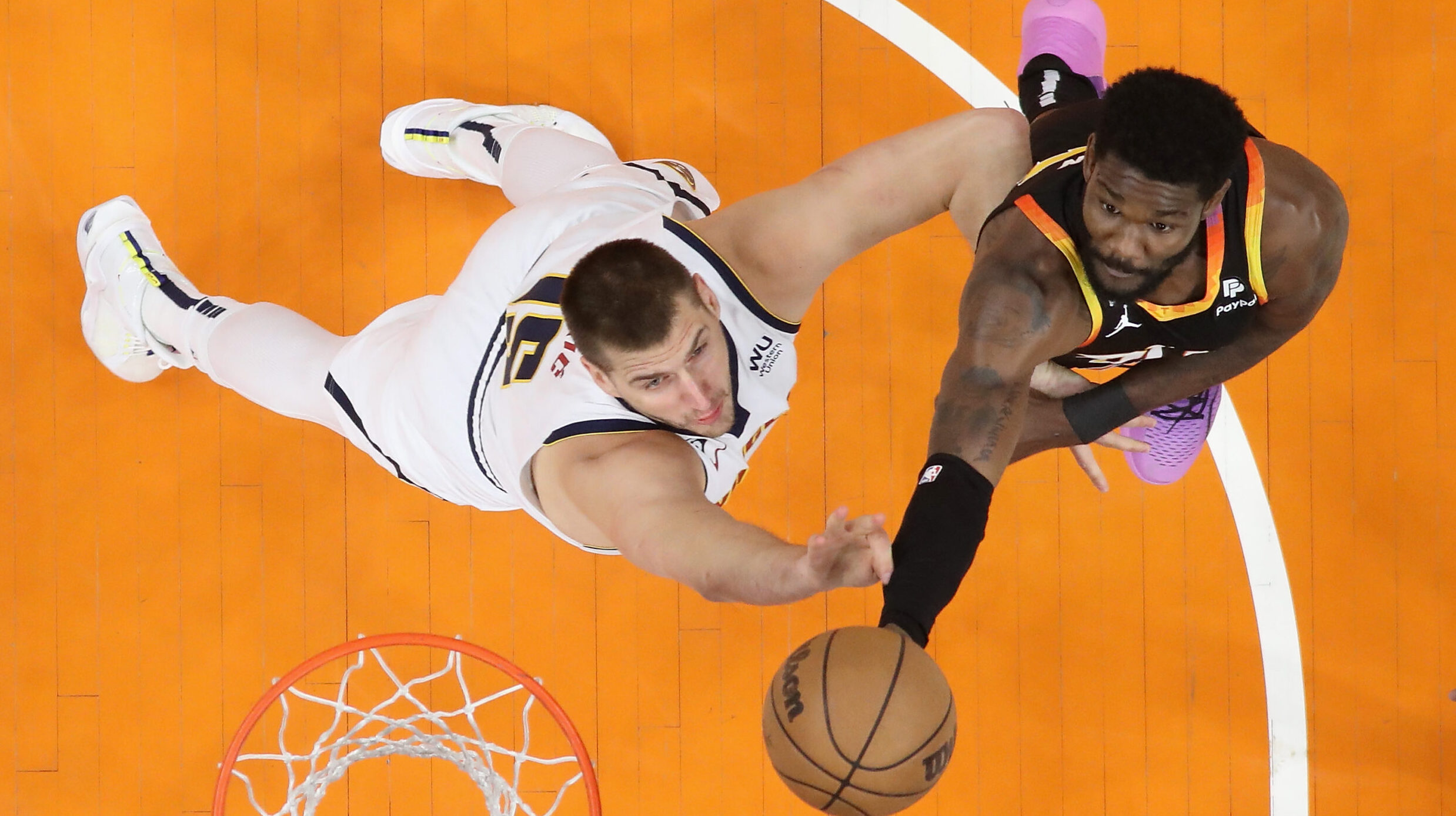 Deandre Ayton #22 of the Phoenix Suns attempts a shot over Nikola Jokic #15 of the Denver Nuggets d...
