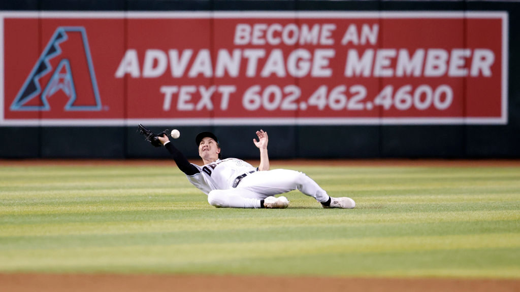 Jake McCarthy #31 of the Arizona Diamondbacks drops the ball while attempting a diving catch during...