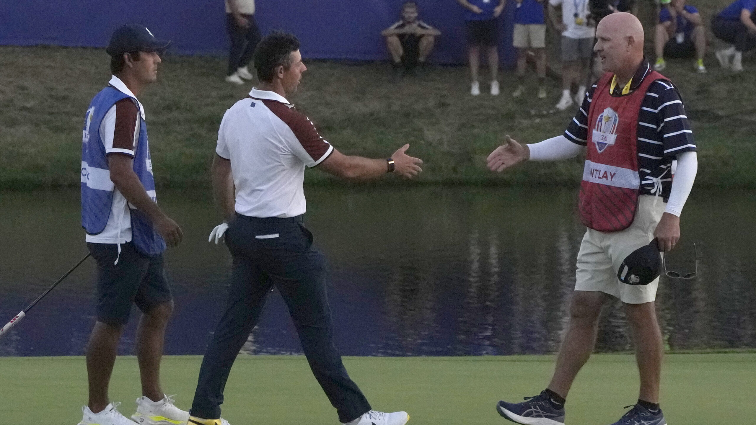 Europe's Rory Mcilroy, center, goes to shake hands with United States' Patrick Cantlay 's caddie Jo...