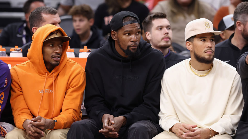 Bradley Beal #3, Kevin Durant #35 and Devin Booker #1 of the Phoenix Suns watch from the bench duri...
