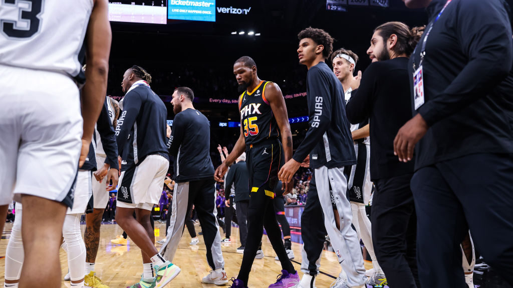 Kevin Durant #35 of the Phoenix Suns walks off the court amid the San Antonio Spurs bench after mis...