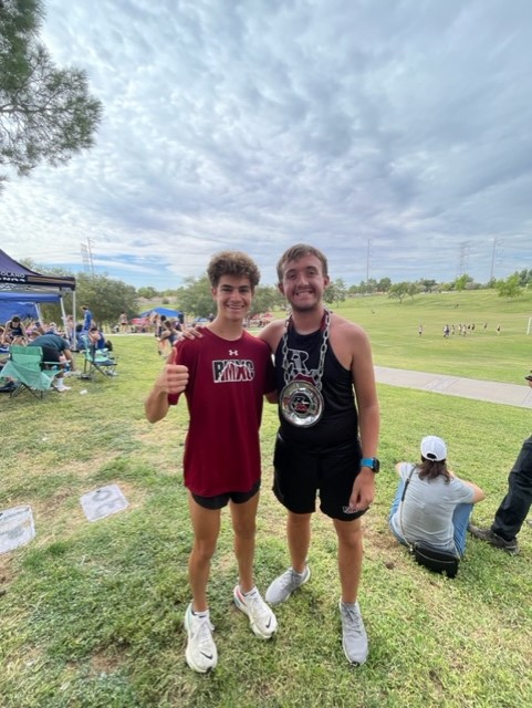 Matt Hamilton (left) poses for a photo with a teammate at a cross country meet....