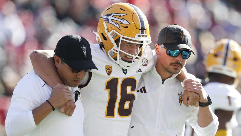Trenton Bourguet #16 of the Arizona State Sun Devils reacts as he is helped off the field by traini...