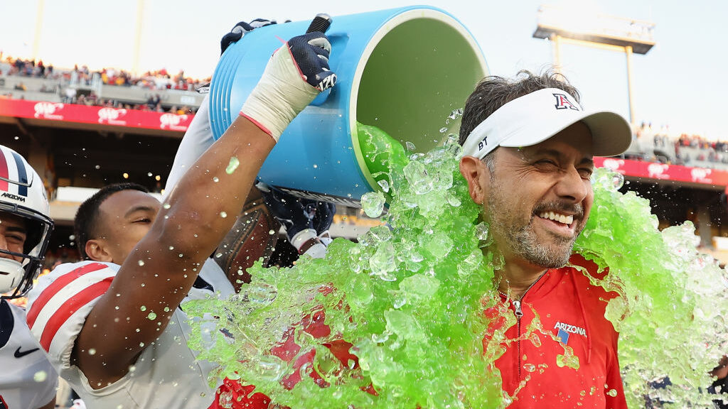 Head coach Jedd Fisch of the Arizona Wildcats is dunked with powerade from Jacob Manu #5 during the...